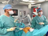 Chirurgové při laparoskopické operaci za pomoci robotického ramene